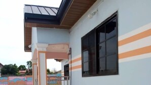 A building with a tiled patio, a window with black frames, and a metal railing. - Dukusguest (Kumasi)