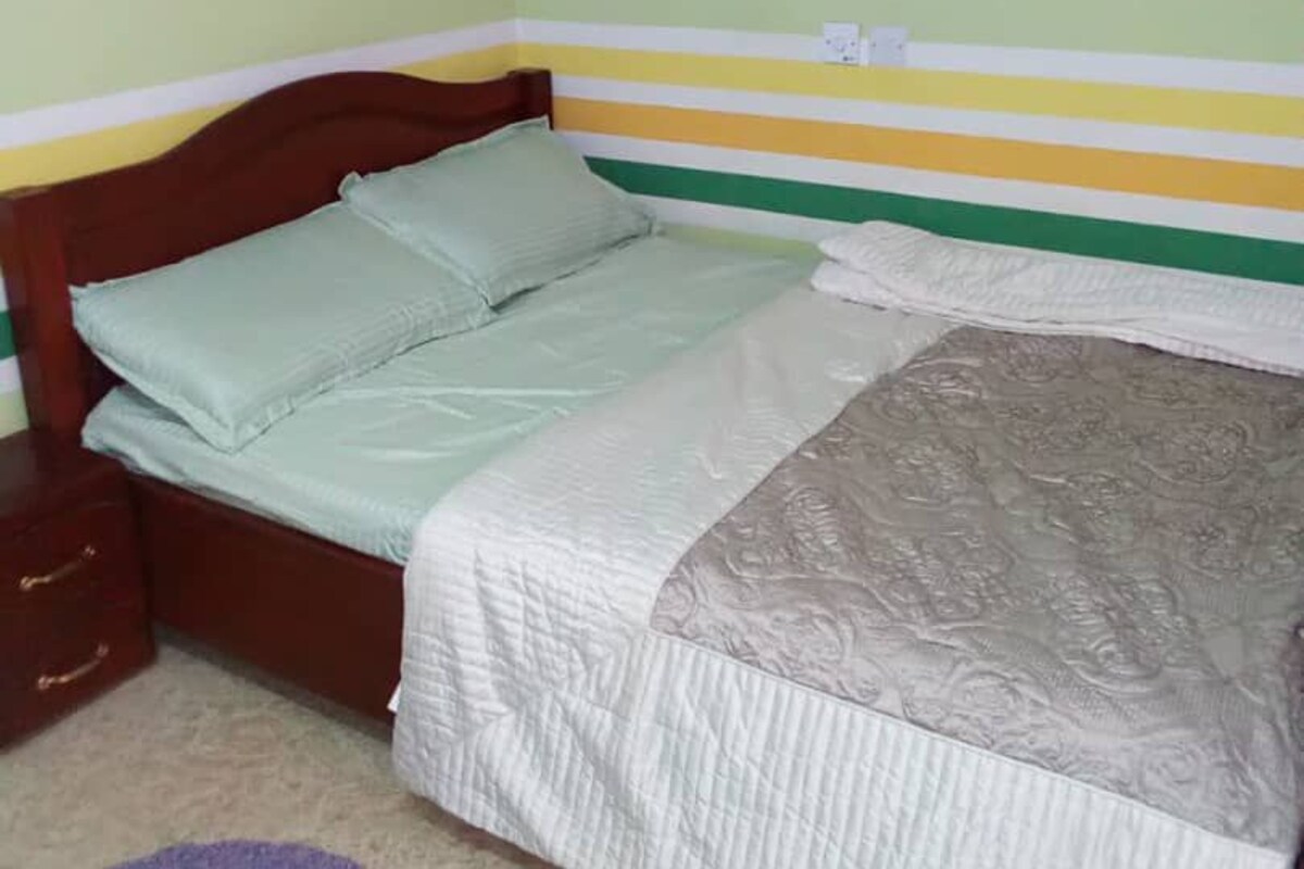 A single bed with a wooden headboard in a room with green walls and colorful stripes.