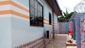 A covered patio area with patterned tiles, a window, and a door. - Dukusguest (Kumasi)
