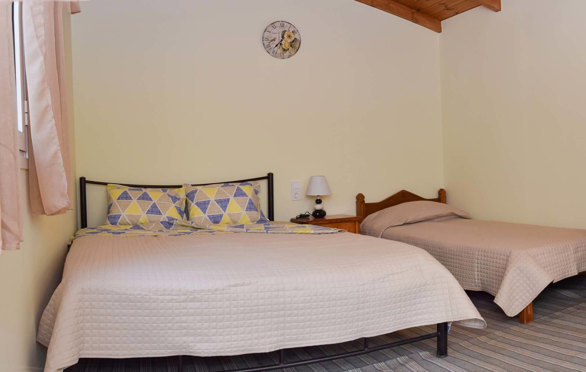 Un dormitorio con dos camas, un reloj en la pared y una lámpara en la mesita de noche.