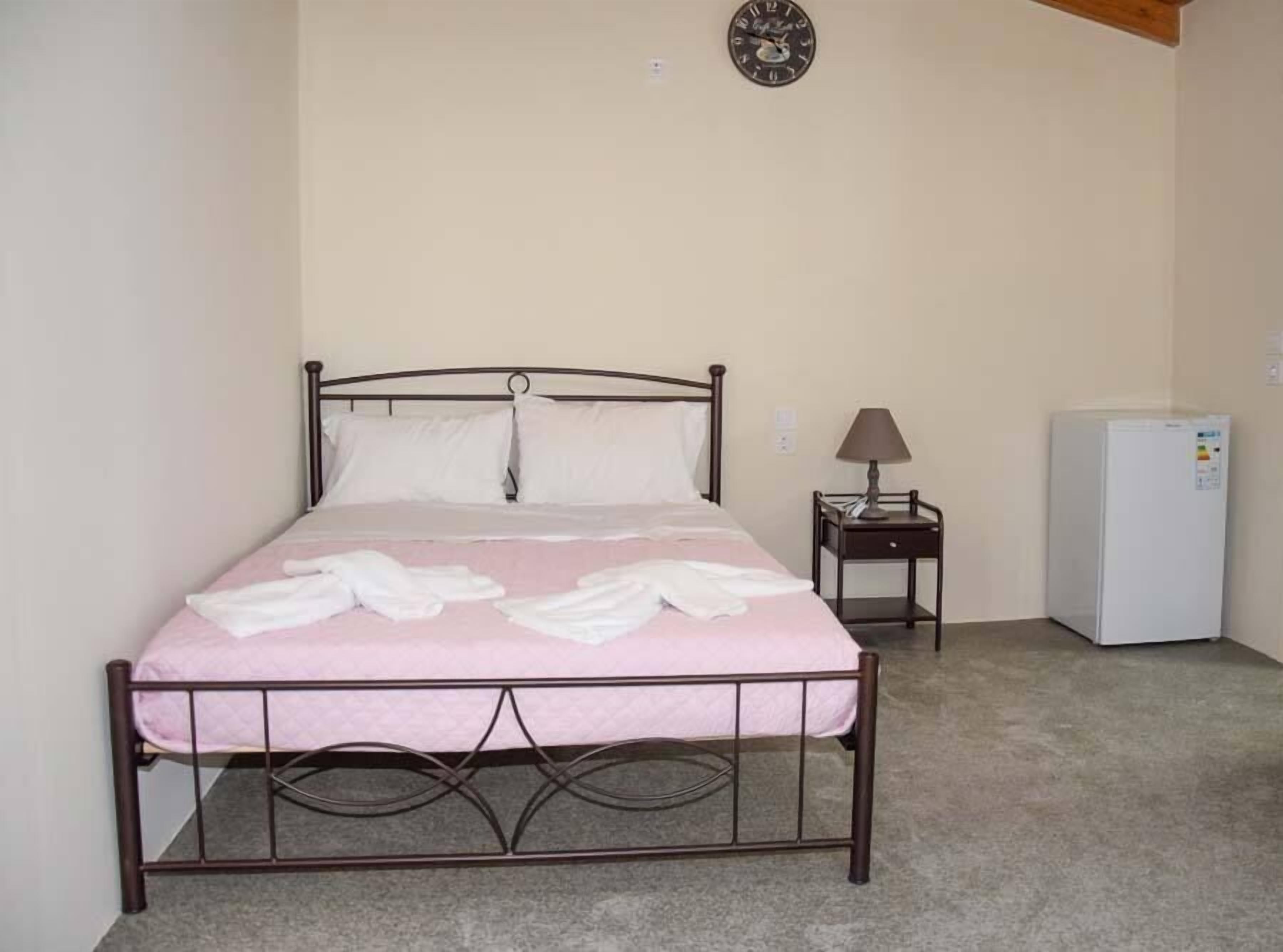 Un lit simple avec un cadre en métal, une table de chevet avec une lampe et un réfrigérateur blanc.