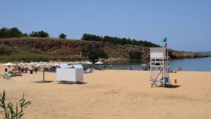 Una playa con torres de salvavidas, sombrillas y sillas.
