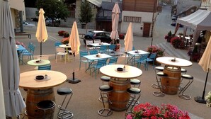 Un café al aire libre con mesas y sillas, sombrillas y vista a la calle.