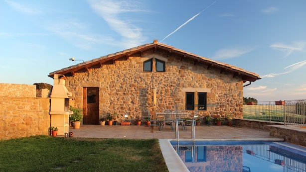 A stone house with a pool, outdoor seating, and a clear sky. - Quiet and cozy house (Vilaplana la Baronia de Rialb Lleida)