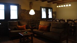 A cozy living room with a stone wall, wooden furniture, and a hanging light fixture. - Quiet and cozy house (Vilaplana la Baronia de Rialb Lleida)