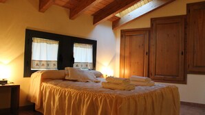 A bedroom with a bed, two windows with curtains, a wooden wardrobe, and a nightstand. - Quiet and cozy house (Vilaplana la Baronia de Rialb Lleida)
