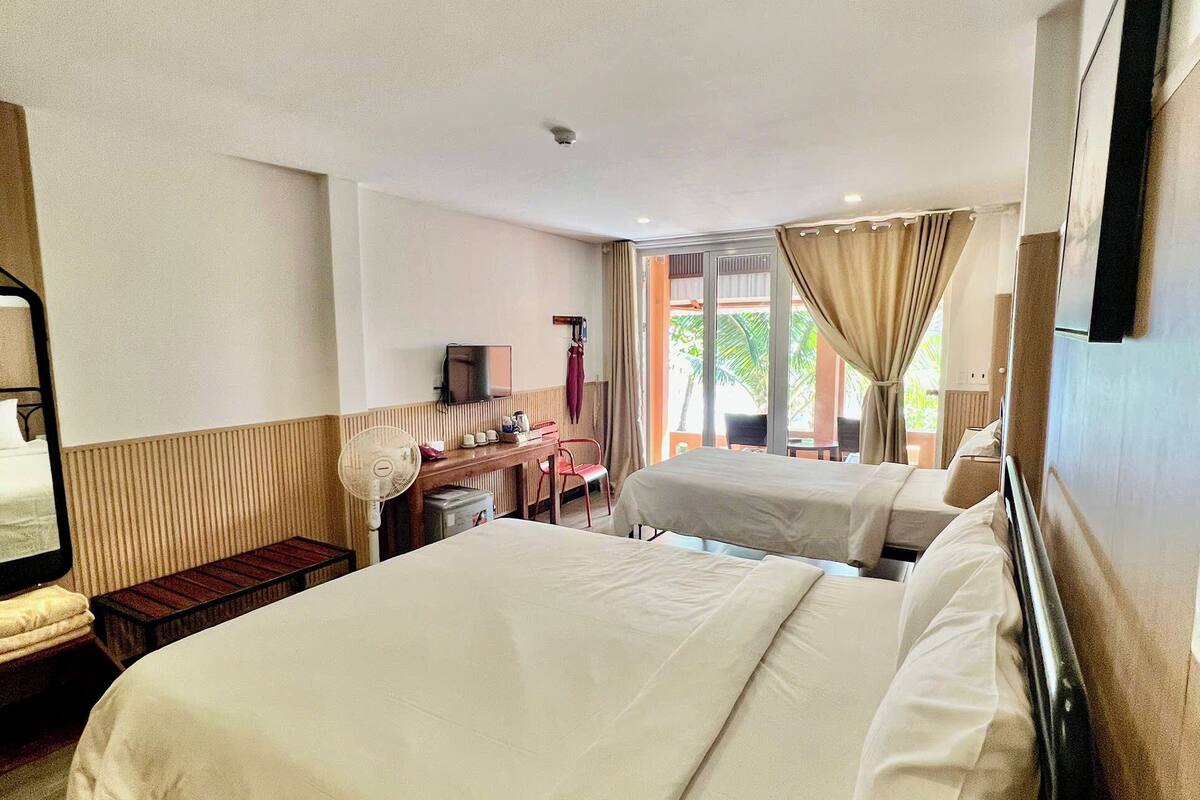 A hotel room with a large bed, a desk, a chair, and a television.