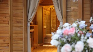 Interno di una baita in legno con zona doccia e una panca di legno.