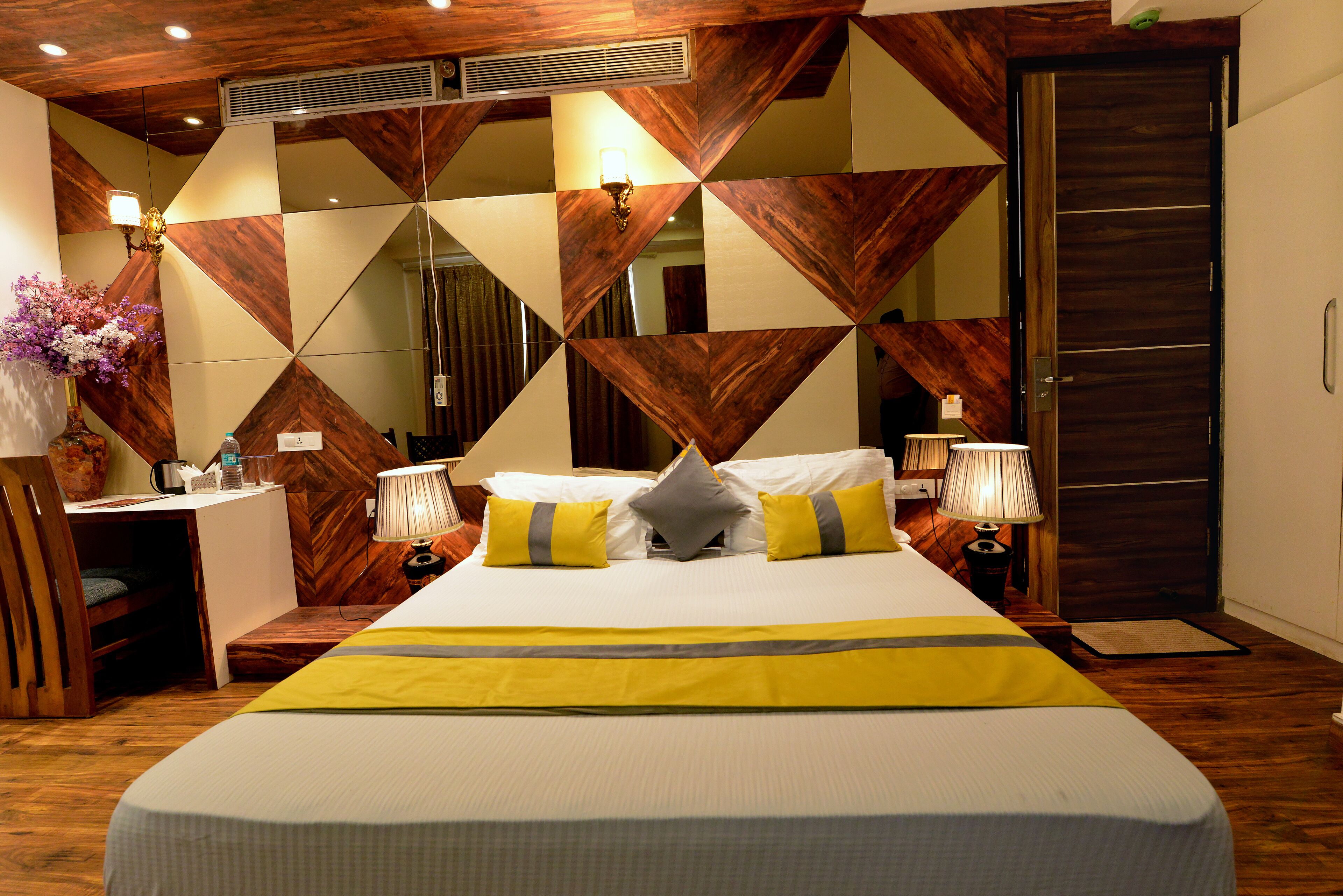 Una habitación de hotel con una cama grande, dos mesitas de noche, un escritorio y un armario.