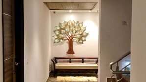 A hallway with a bench, a directional sign, and a decorative tree sculpture.