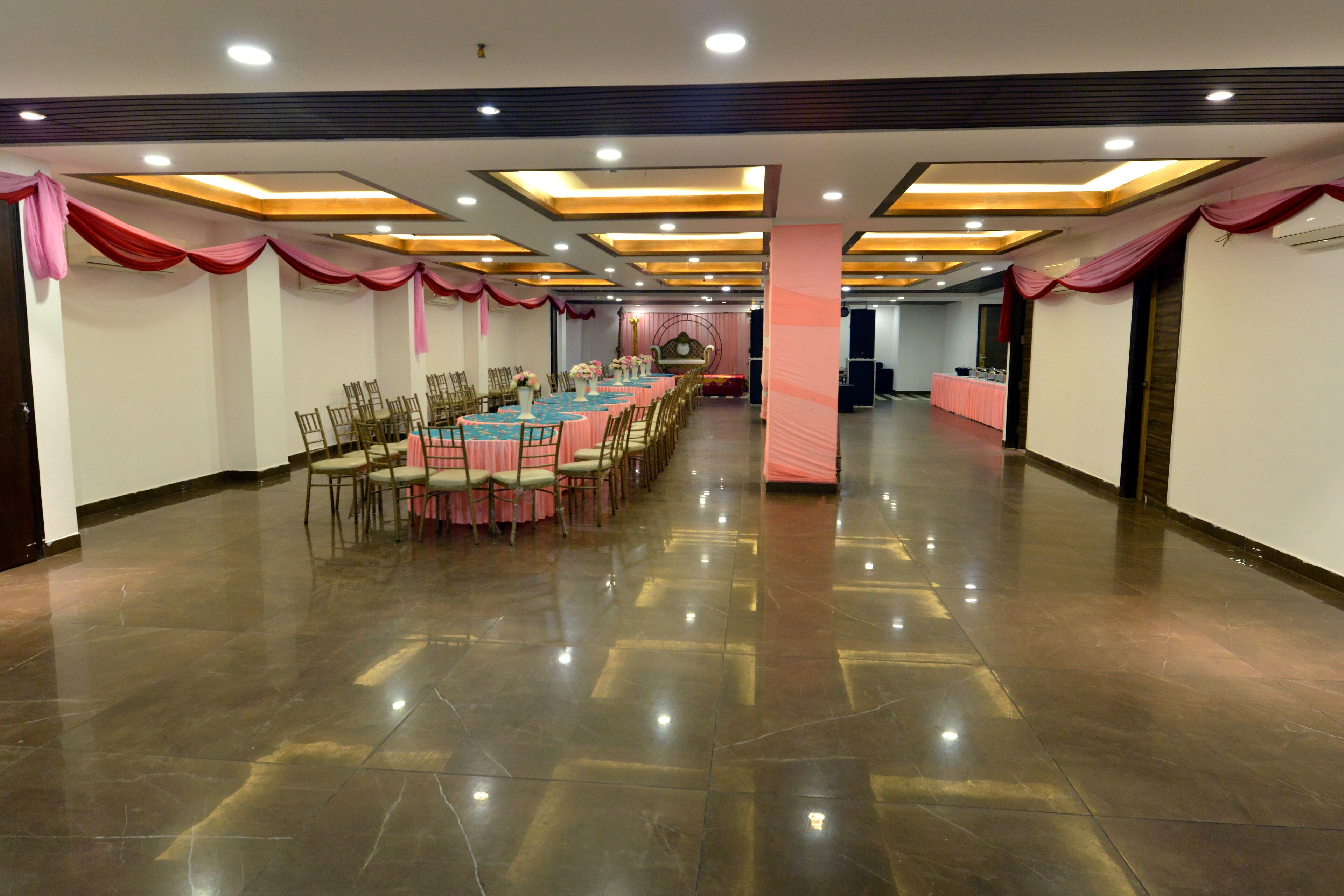 A spacious banquet hall with a long table set for a formal event, surrounded by chairs.
