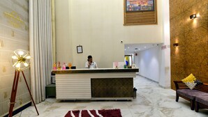 A reception area with a marble floor, a reception desk, a framed picture on the wall, and a bench with a cushion.
