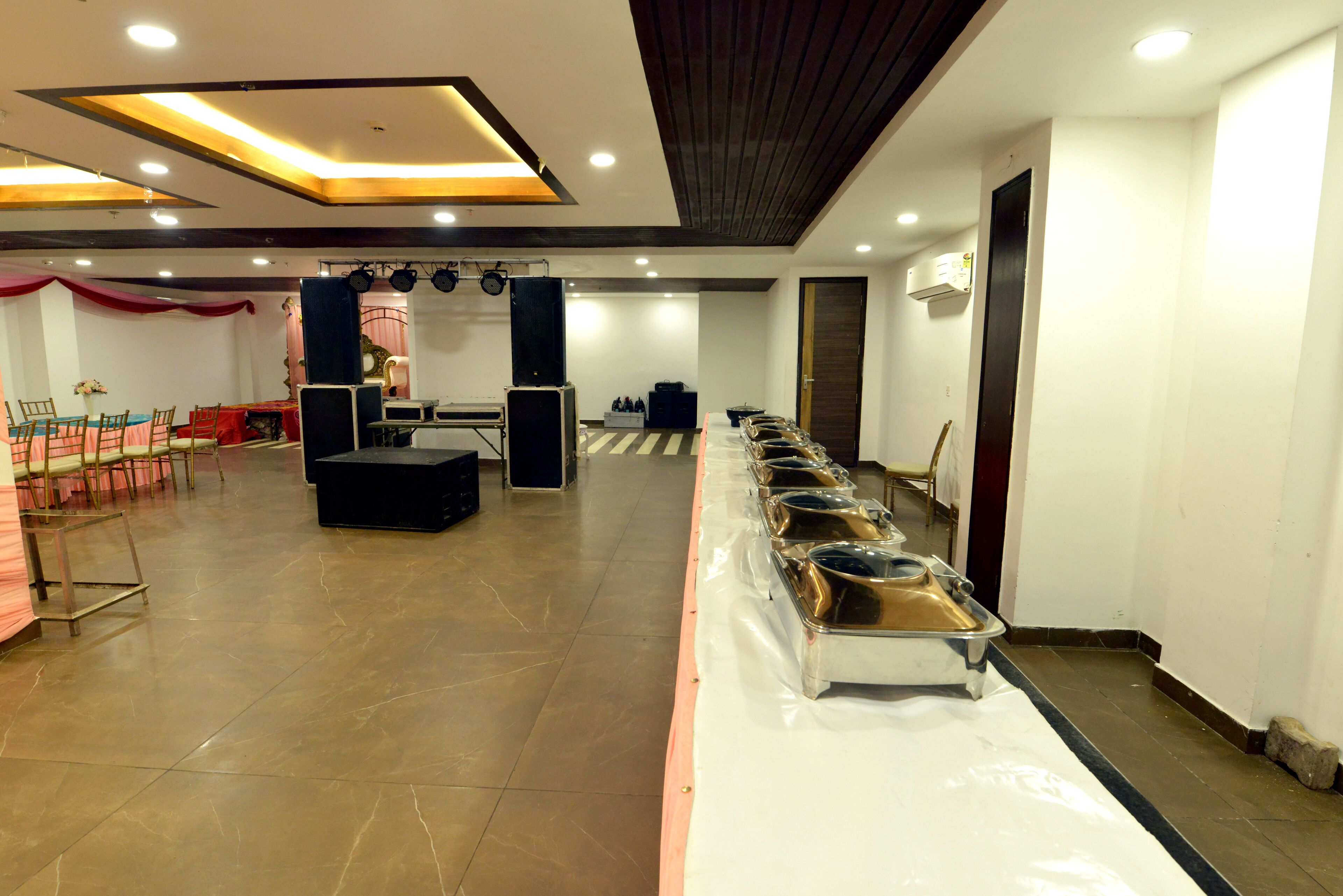 A banquet hall with a long table set for a meal, a stage with musical instruments, and a seating area with chairs.