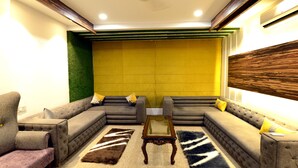 A modern living room with a sectional sofa, a glass coffee table, and decorative rugs.