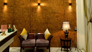A lobby with a marble floor, a clock, two sofas with cushions, a lamp, and a curtain.