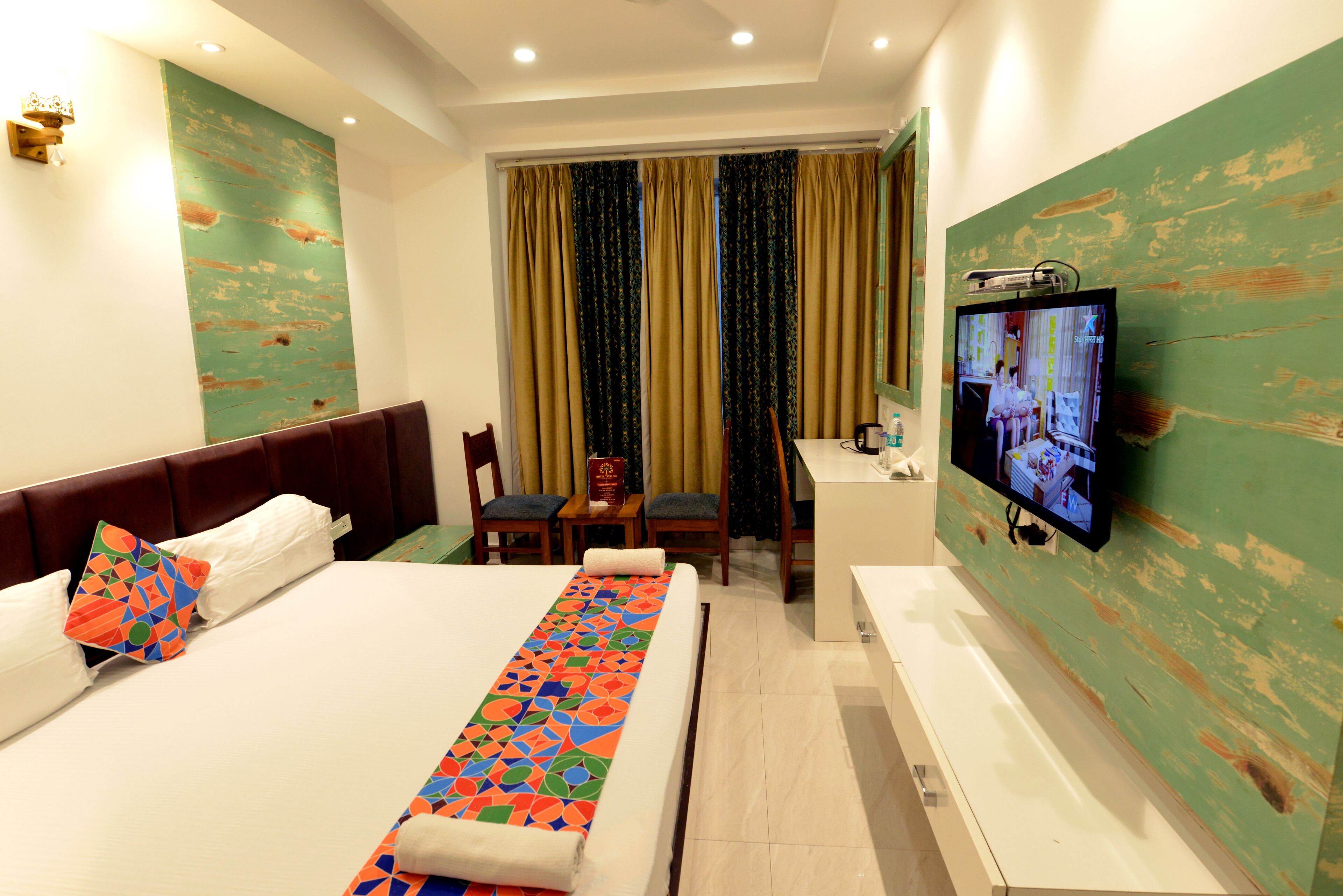 A hotel room with a large bed, a desk, a chair, a television, and a bathroom.