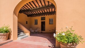 Un patio al aire libre con suelo de ladrillo, una pérgola de madera y plantas en macetas.