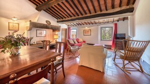 Amplia sala de estar con mesa de comedor de madera, asientos cómodos y un techo alto con vigas a la vista.