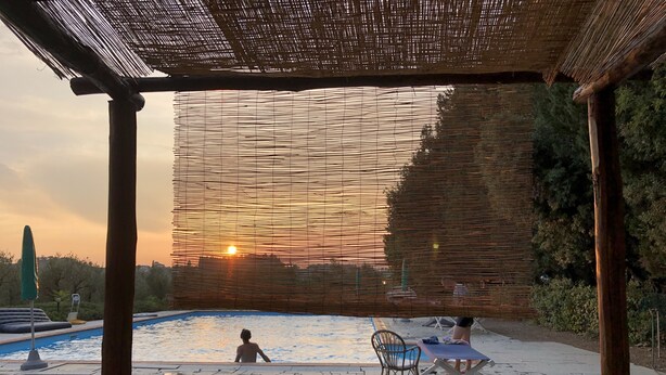 Un área de piscina con una pérgola, una silla de descanso y una mesa.