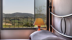 Un dormitorio con vistas a un paisaje verde a través de una ventana.