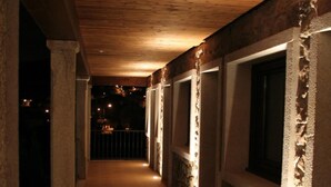 A corridor with stone walls and wooden ceiling, leading to rooms with windows. - Hotel A Maquía (Poio)