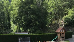 A well-maintained grassy area with a wooden playhouse, a swing set, and a trampoline. - Chambres d'Hotes Maison Efftermatten (Andlau)