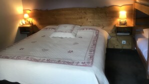 A bed with a quilted headboard, two bedside lamps, and a wooden nightstand. - Chambres d'Hotes Maison Efftermatten (Andlau)