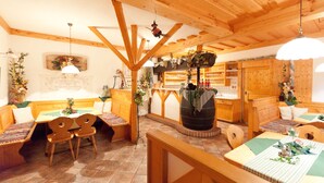 A cozy wooden interior with a long communal table, benches, and a rustic kitchen area. - Weingut Seiner vlg. Kraxner (Sankt Stefan ob Stainz)
