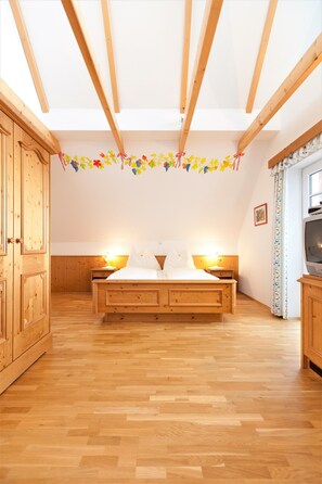 Un dormitorio con cama de madera, armario de madera y televisor sobre un mueble.