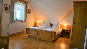 A bedroom with a wooden bed, a radiator, a window with curtains, and a wooden wardrobe. - Weingut Seiner vlg. Kraxner (Sankt Stefan ob Stainz)
