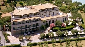 Un hotel de varios pisos con un patio central, zona de estacionamiento y vistas al mar.