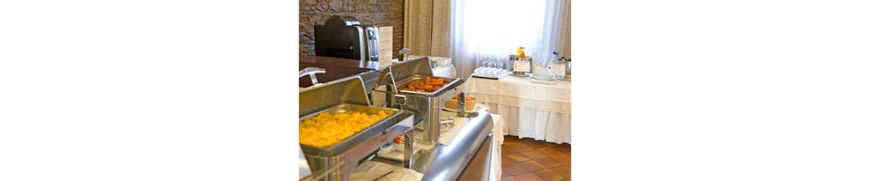 A buffet setup with various food items in metal containers, a coffee machine, and a menu stand.
