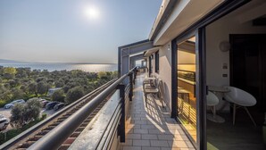 Un balcón con vista al mar, un área de comedor con sillas y mesas, y un diseño arquitectónico moderno.