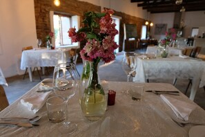 Una mesa de comedor preparada con copas de vino, un florero con flores y una vela.