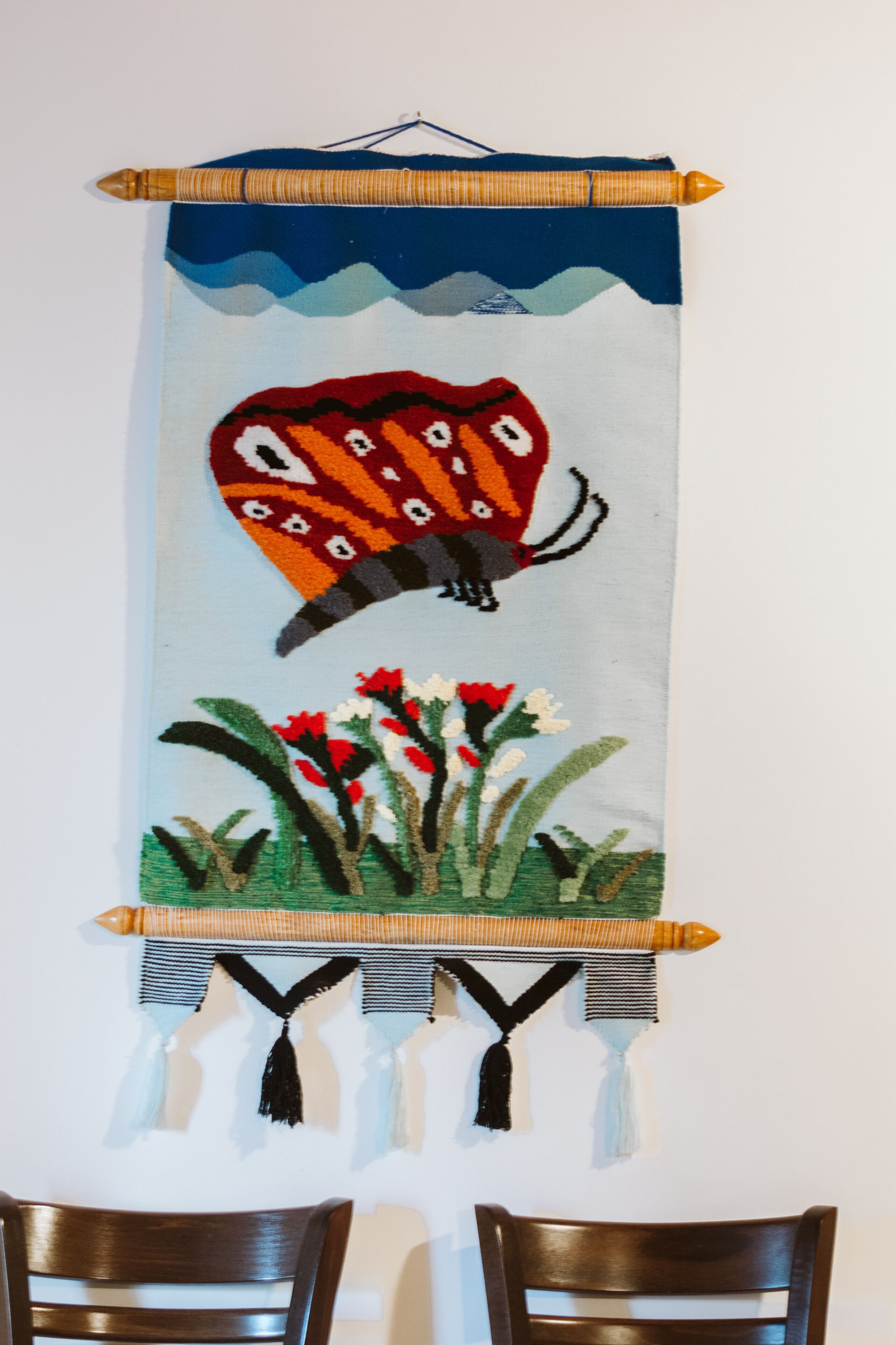 A wall hanging with a bird and flowers.