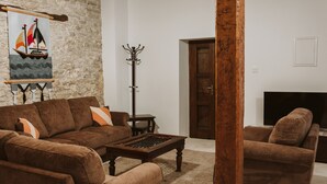 A living room with a brown sofa set, a wooden coffee table, and a coat rack. - Ariadni Gaia Cottage (Limassol)