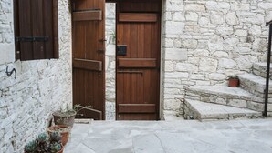 A stone wall with a wooden door and a potted plant. - Ariadni Gaia Cottage (Limassol)