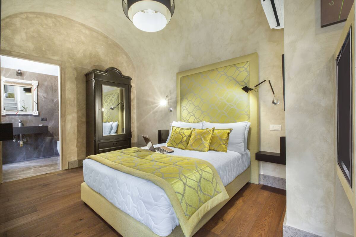 A bedroom with a bed, a mirror, a nightstand, and a built-in desk.