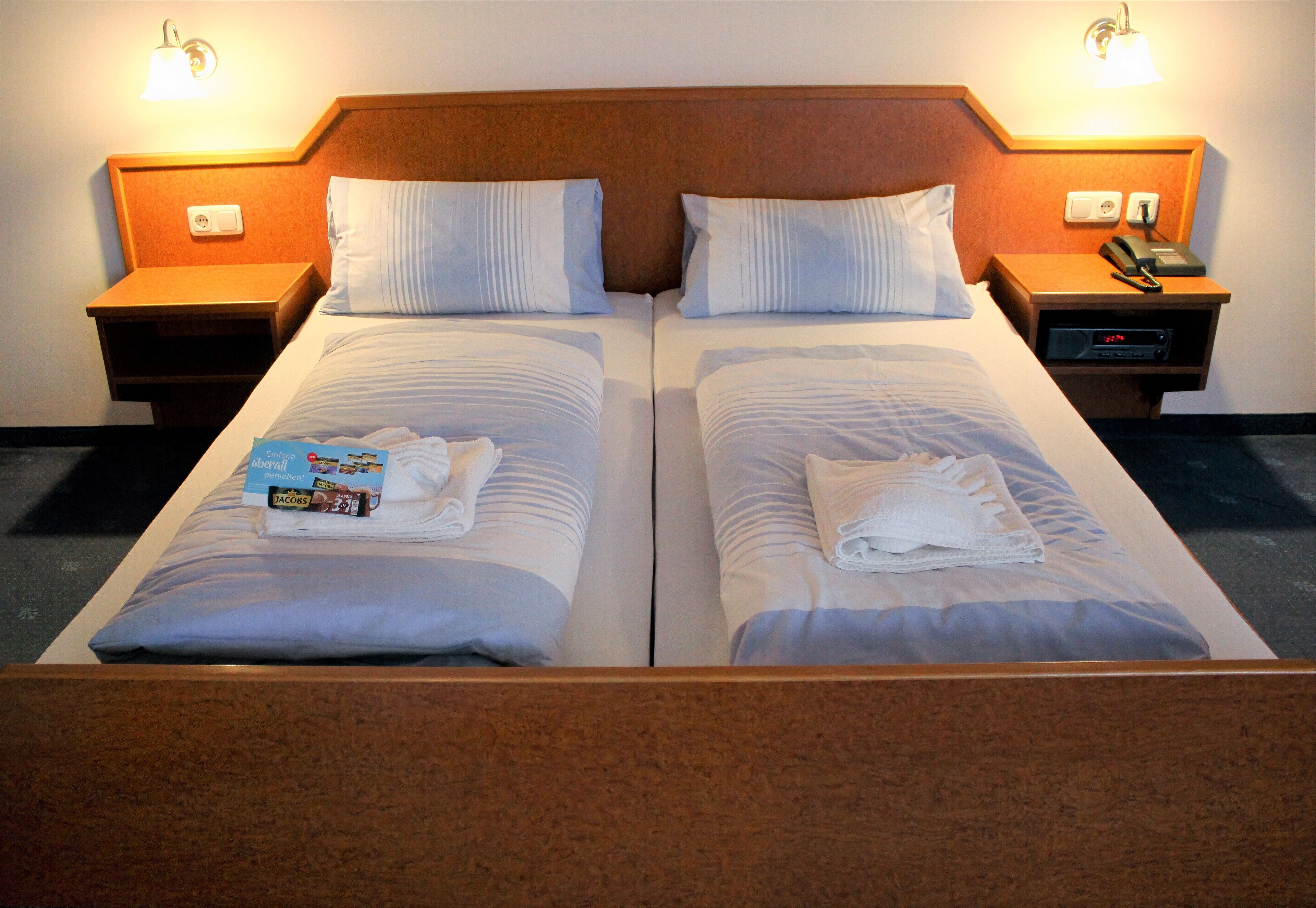 Een tweepersoonsbed met twee nachtkastjes, elk met een lamp en een telefoon.