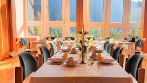 A dining area with tables set for service, large windows, and a view of greenery outside. - Waldhotel Feldbachtal (Neuhaus am Rennweg)