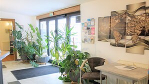 A reception area with a desk, a chair, potted plants, and a world map on the wall. - Waldhotel Feldbachtal (Neuhaus am Rennweg)