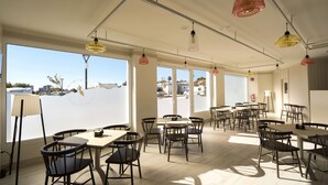 A spacious dining area with multiple tables and chairs, large windows offering a view of the outside, and pendant lighting. - Camping Sol de Calpe Boreal - Caravan park (Calpe)