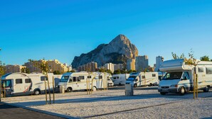 A parking lot with RVs and a large rock formation in the background. - Camping Sol de Calpe Boreal - Caravan park (Calpe)