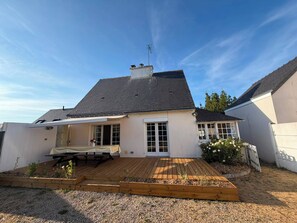 A house with a wooden deck, a covered patio, and a white exterior.