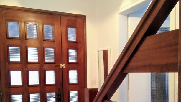 A wooden door with multiple glass panels and a staircase with wooden railings.