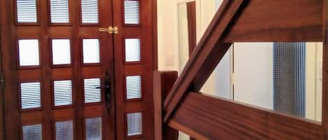 Una puerta de madera con varios paneles de vidrio y una escalera con barandilla de madera.