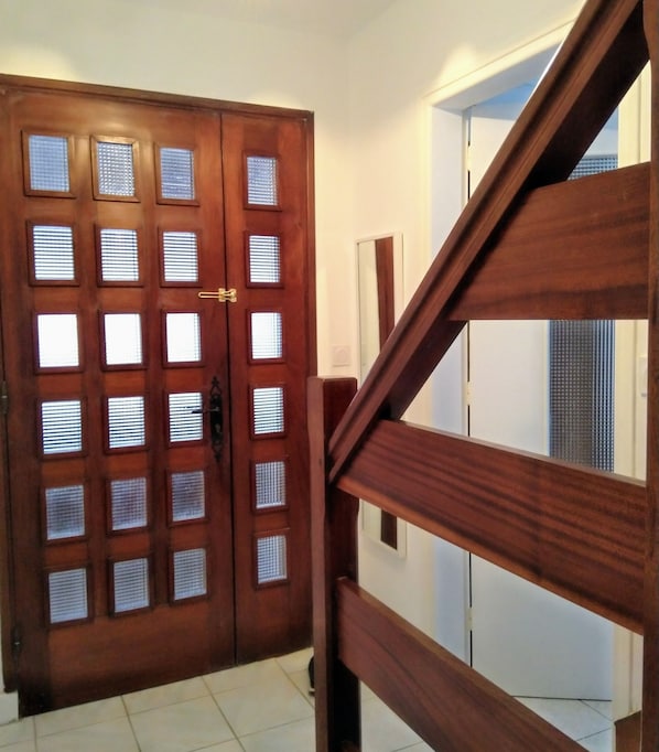 Une porte en bois dotée de plusieurs panneaux de verre et un escalier avec des rampes en bois.