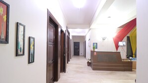 A hotel reception area with a marble floor, wooden doors, and framed artwork on the walls. - Winsome Residency (Noida)