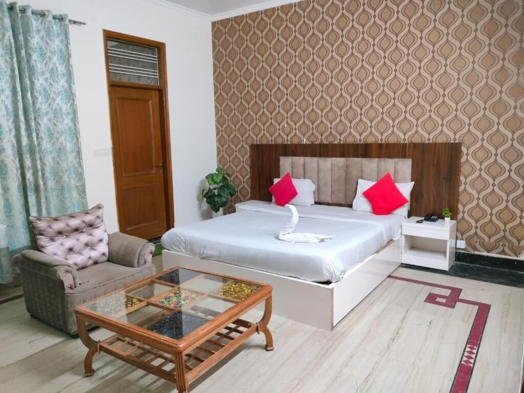 A bedroom with a bed, a glass coffee table, a sofa, a nightstand, and a patterned wall.