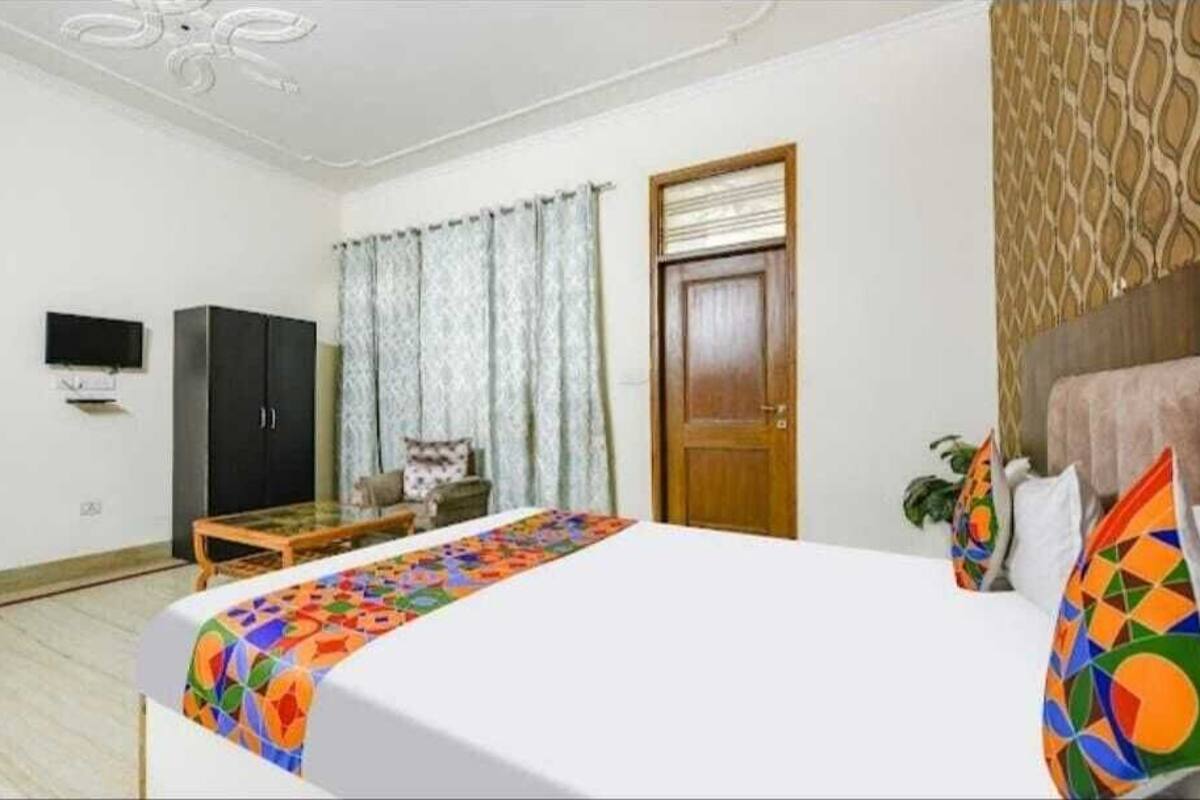 A hotel room with a bed, a TV, a wardrobe, a desk, and a window with curtains.